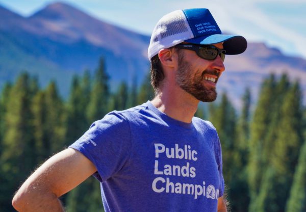 A man standing outside wearing a tshirt that says Public Lands Champion