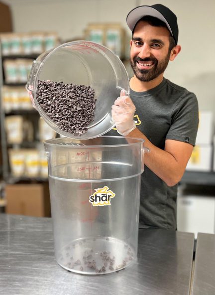 A man with a bucket of chocolate nibs